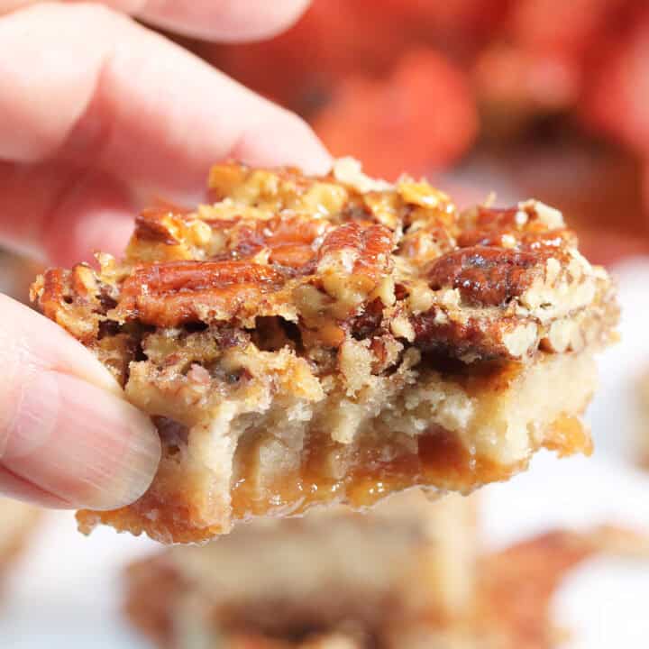 Holding a gooey pecan pie bar with bite out of it.