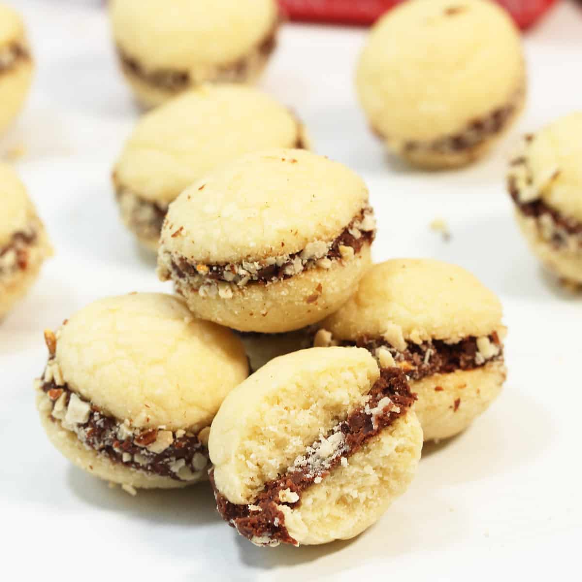 Almond shortbread cookies scattered on table with a bite taken out of front one.