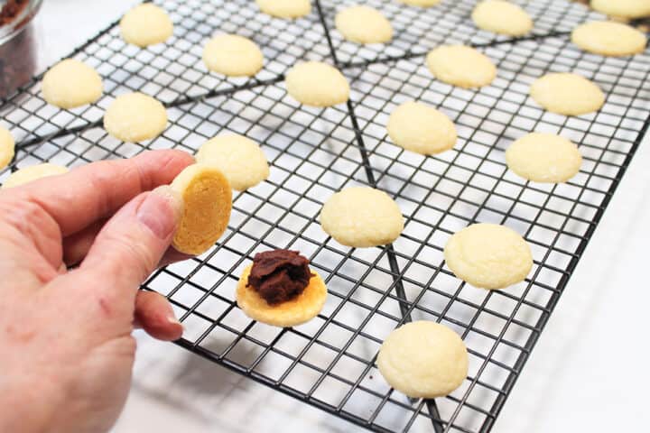 Chocolate filling placed on bottom of cookie and holding cookie to go on top.