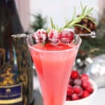 Closeup of cranberry and rosemary garnish on champagne flute.