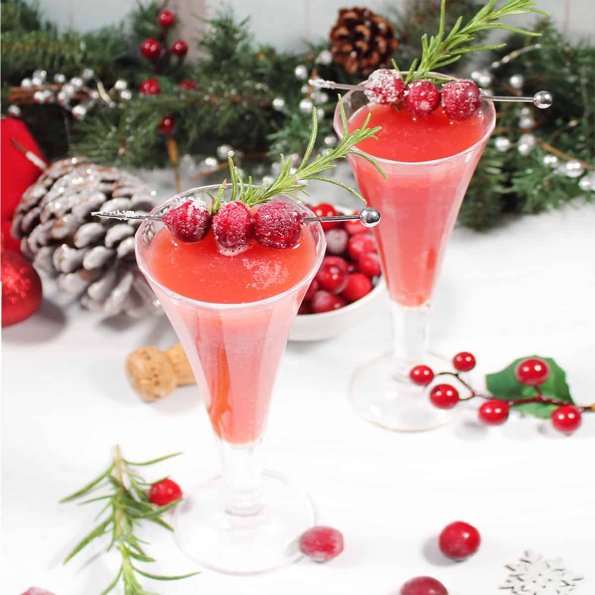 Two cranberry mimosas with scattered cranberries,