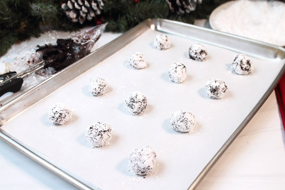 Cookie balls that have been rolled in sugar on cookie sheet.