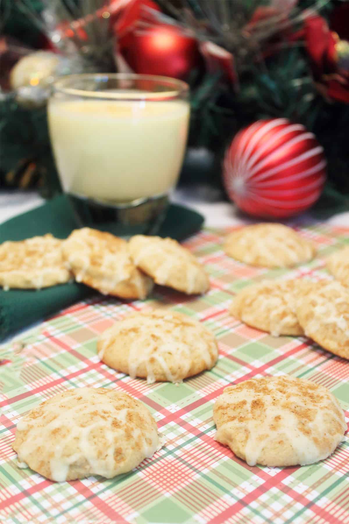 Cookies on plaid placemat with glass of eggnog.