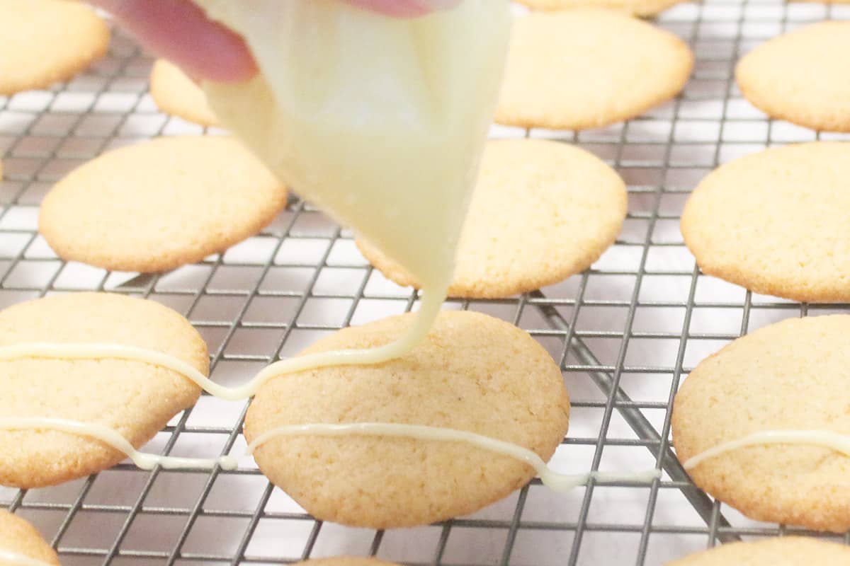 Drizzling eggnog icing on baked cookies.