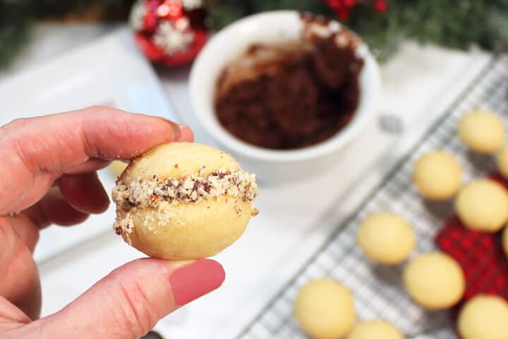 Holding a finished mini sandwich coolie above cookies.