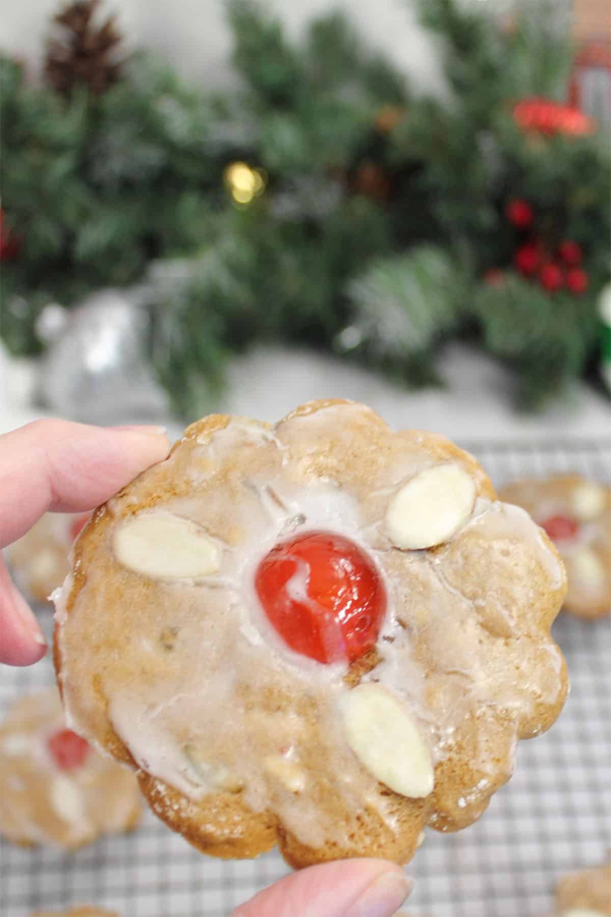 Holding lebkuchen cookie with glaze over cooling rack.