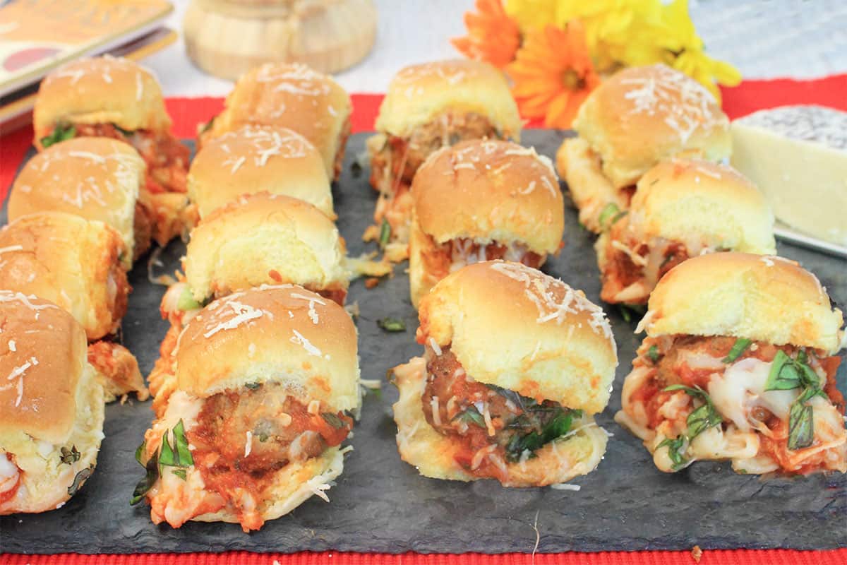 Hot meatball sliders on slate serving board.