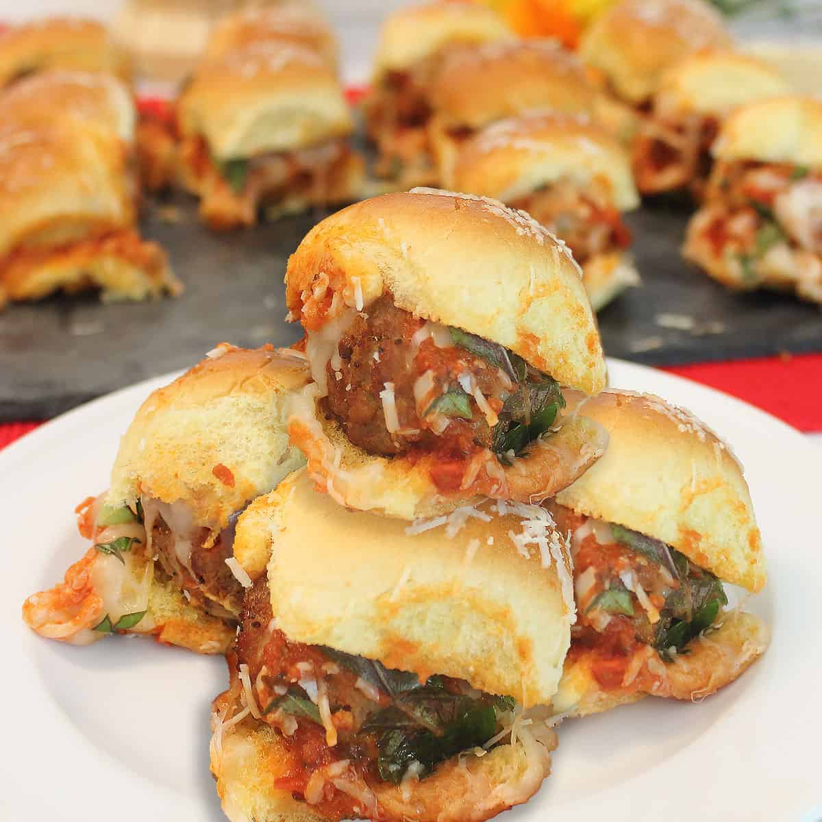 Stacked meatball sliders on white plate.