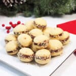 Mini sandwich cookies on white Christmas plate.