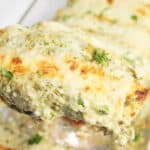 Closeup of a cheesy baked pork enchilada on spatula.