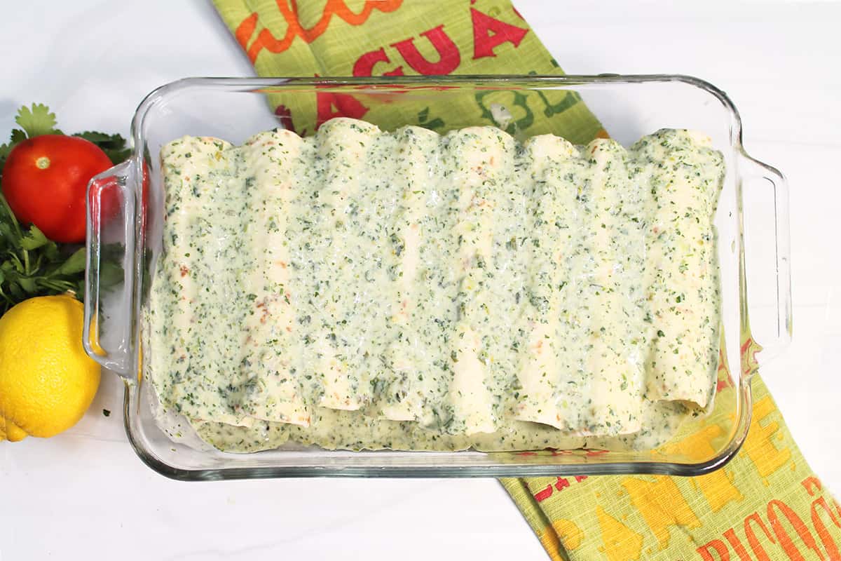 Overhead of tortillas covered with green chile sauce.