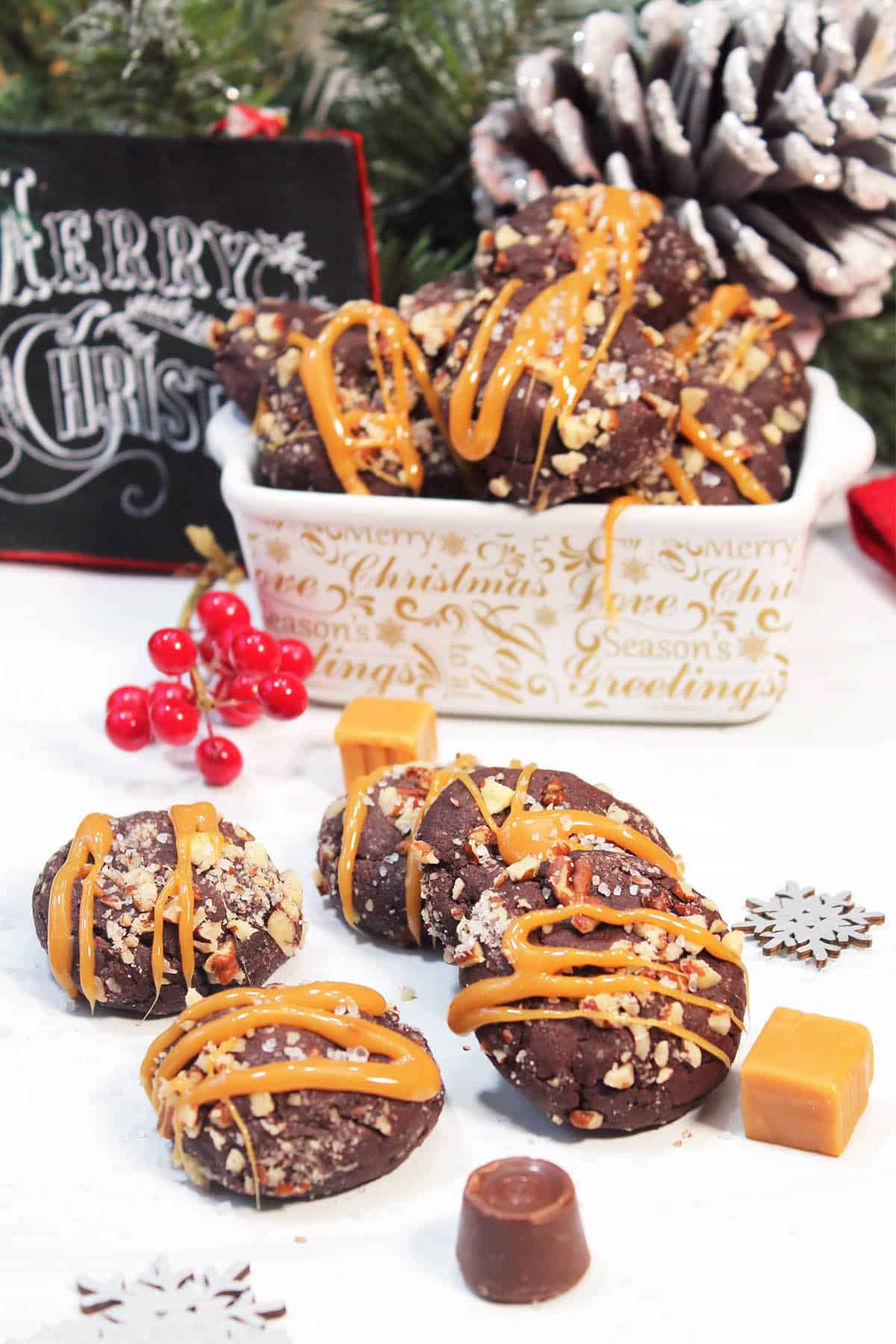 Salted caramel filled chocolate cookies on white table with cookie filled dish in back.