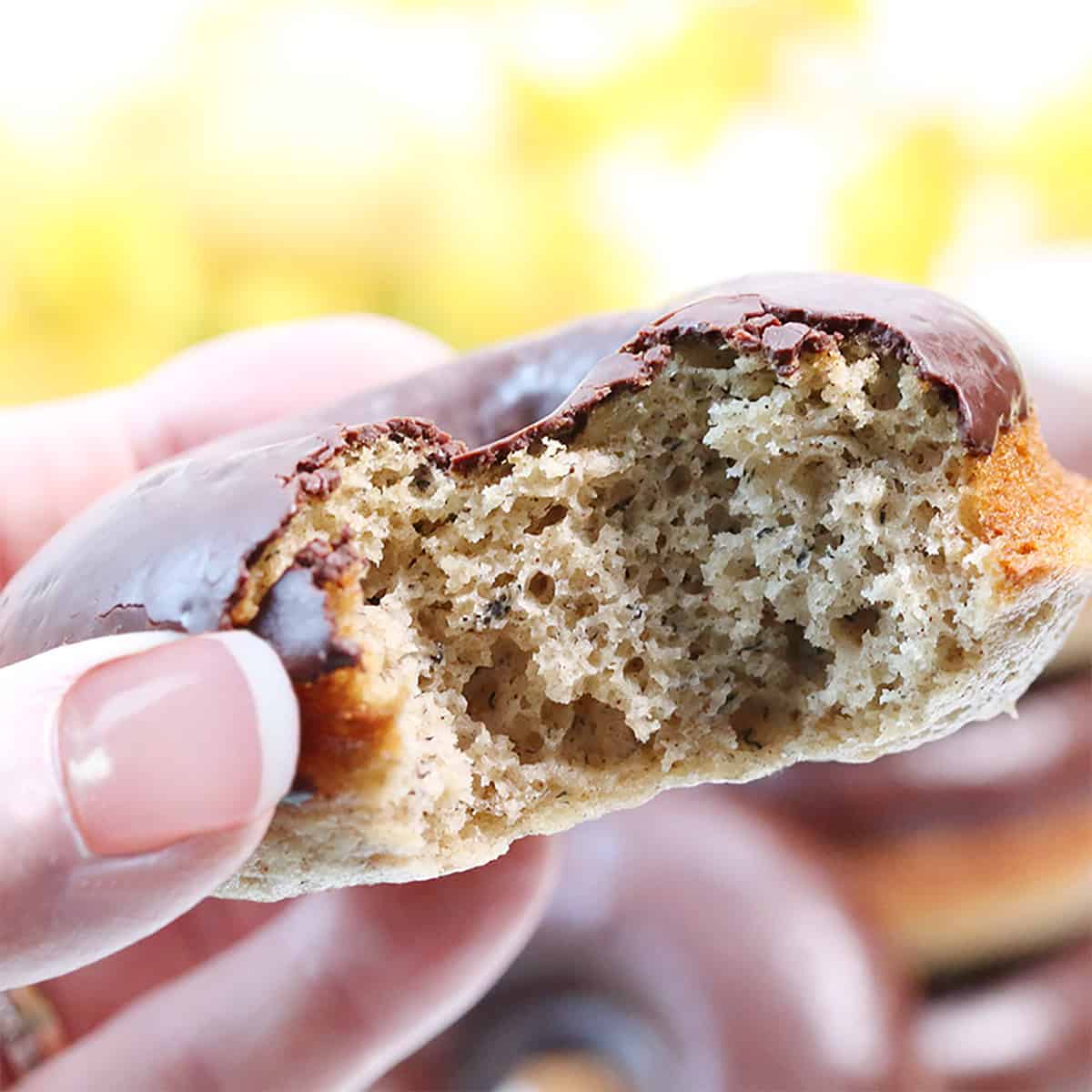 Closeup holding donut with bite taken out of it.