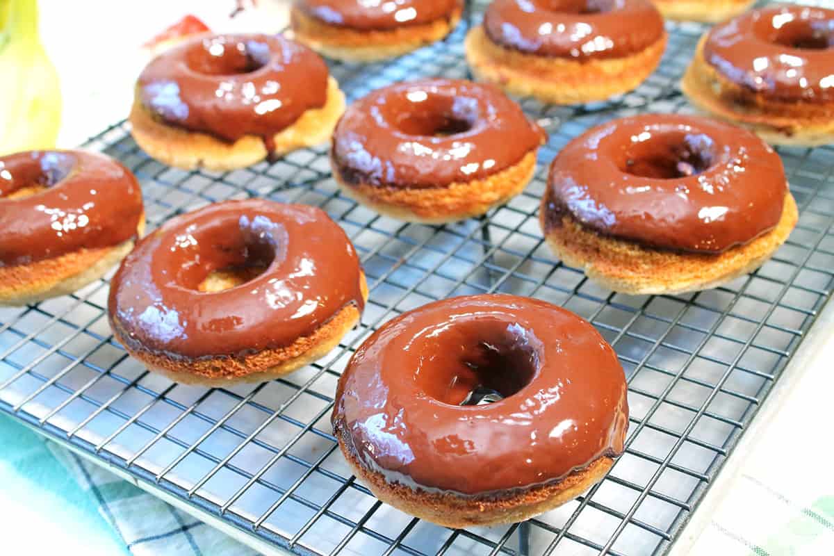 Freshly glazed baked donuts on wire rack.