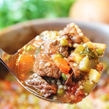 Closeup of ladle of soup over pot.