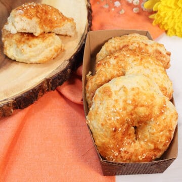 Golden bagels in basket with one cut open.