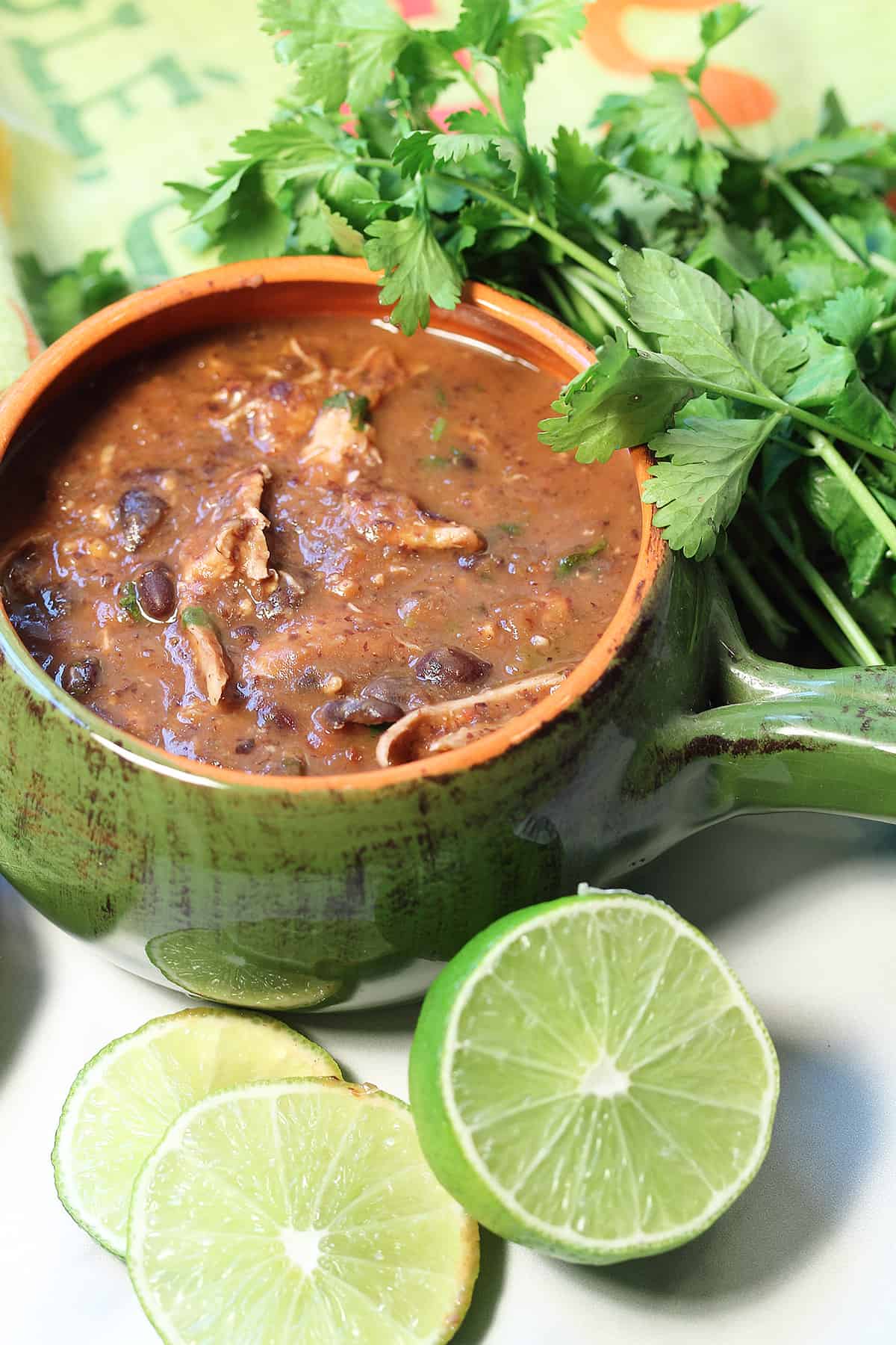 Chicken black bean soup in green bowl with lime and cilantro.