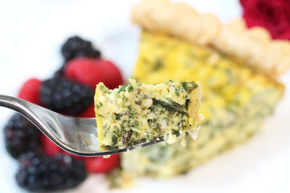 Closeup of bite of spinach artichoke quiche on fork.