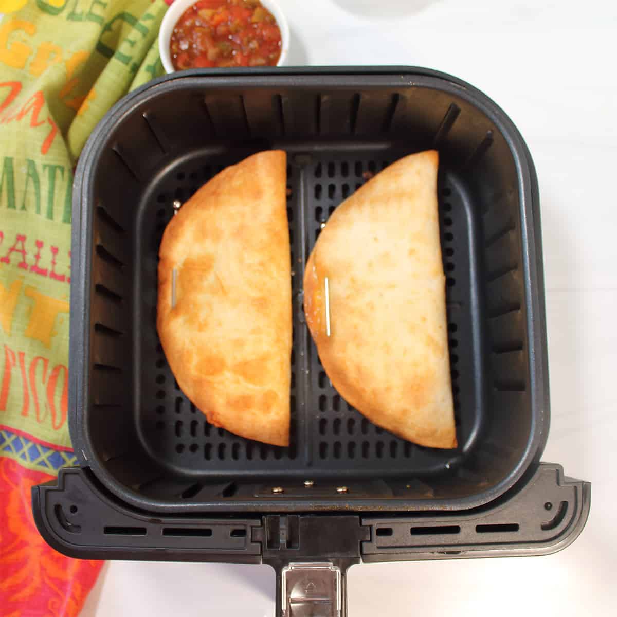 Toasted crispy quesadillas in air fryer basket.