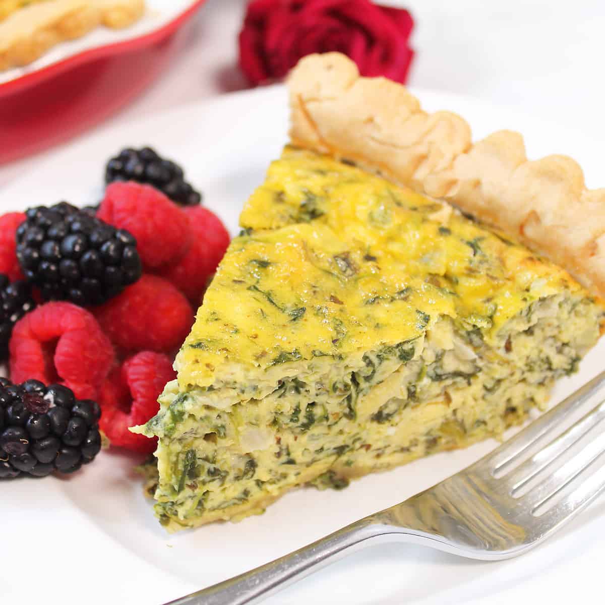 Slice of breakfast quiche on plate with fork.