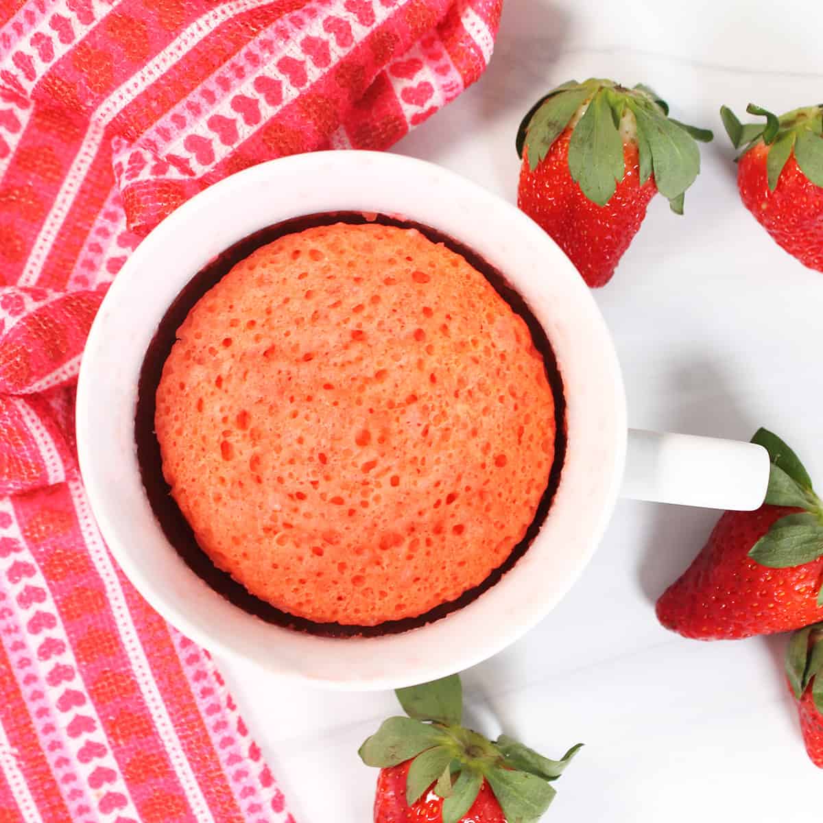 Overhead of strawberry mug cake with strawberries.