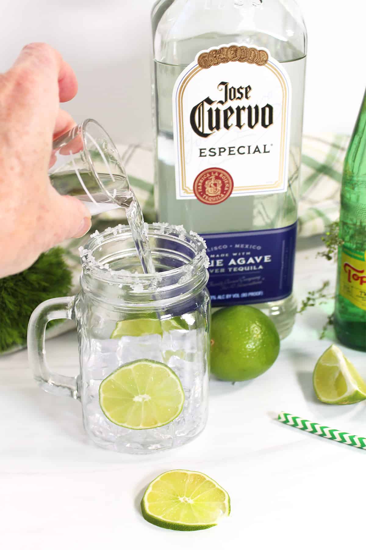 Pouring a jigger of vodka in mason jar.