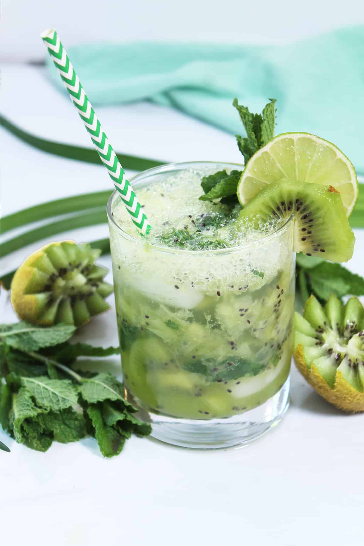 Kiwi Mojito with straw and garnish of lime and kiwi.