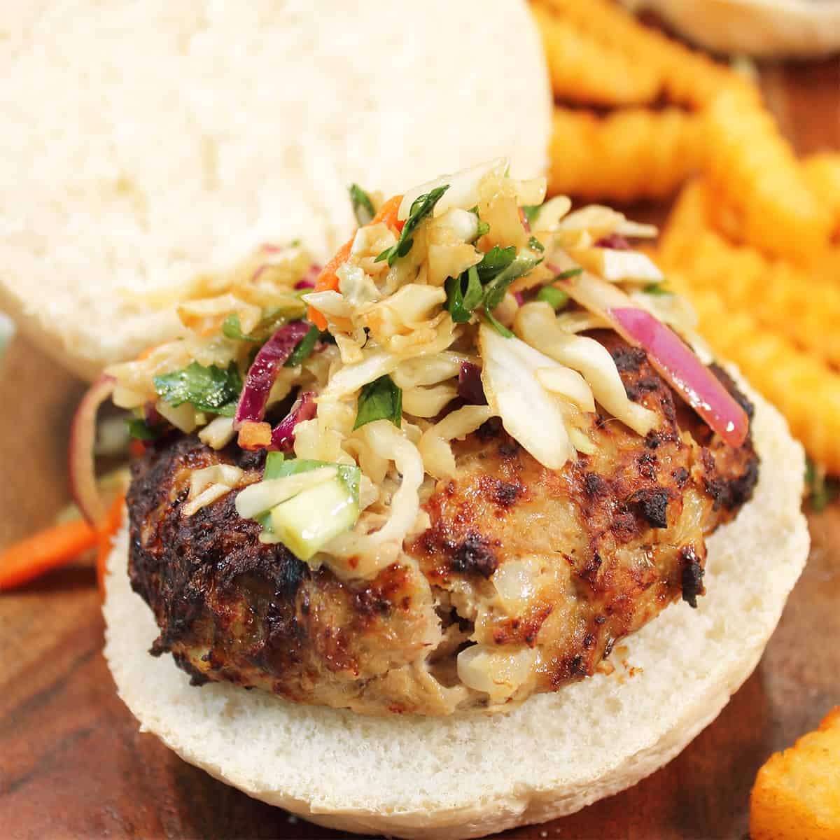 Closeup of air fried turkey burger on roll with crunchy slaw.