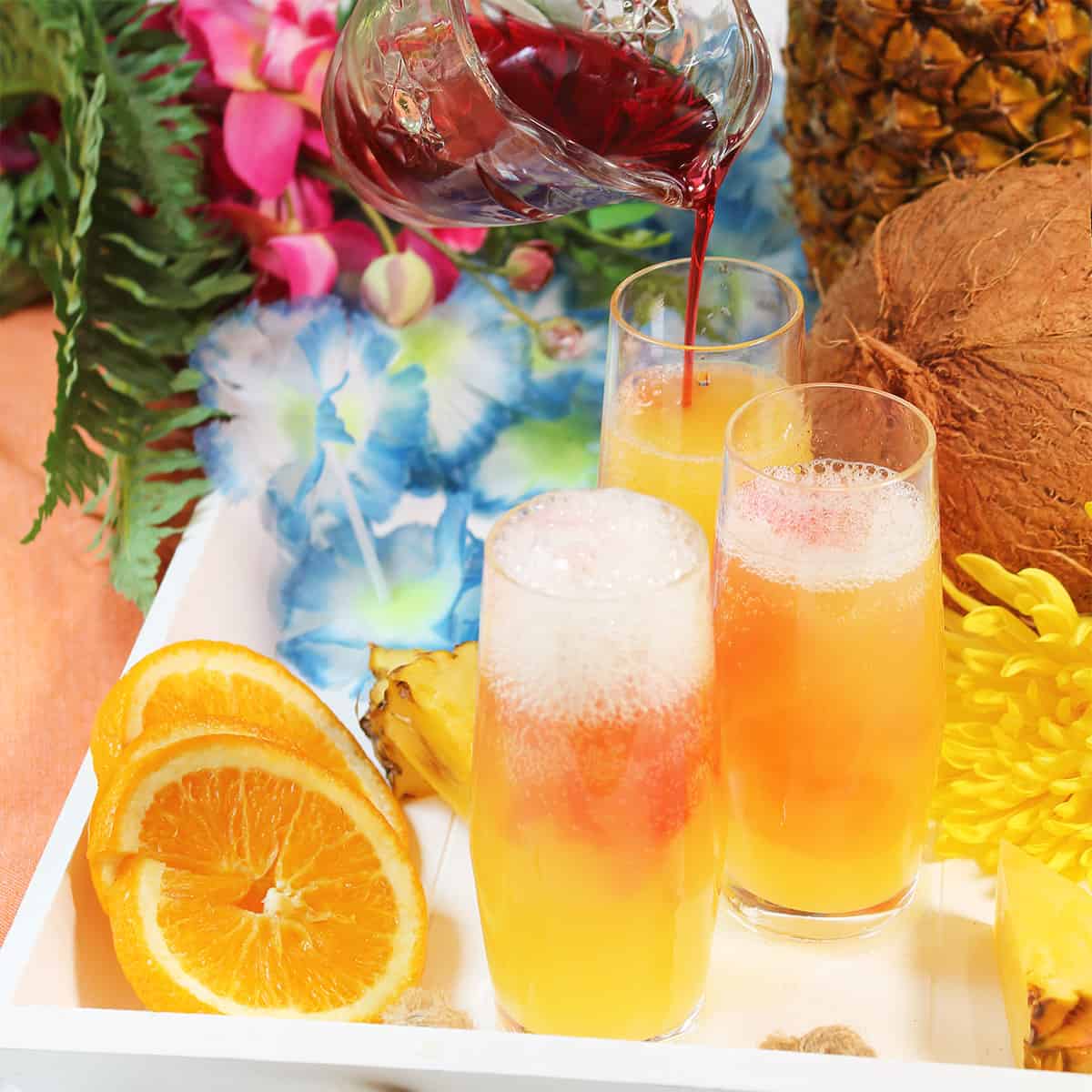 Pouring cranberry juice into mimosas.