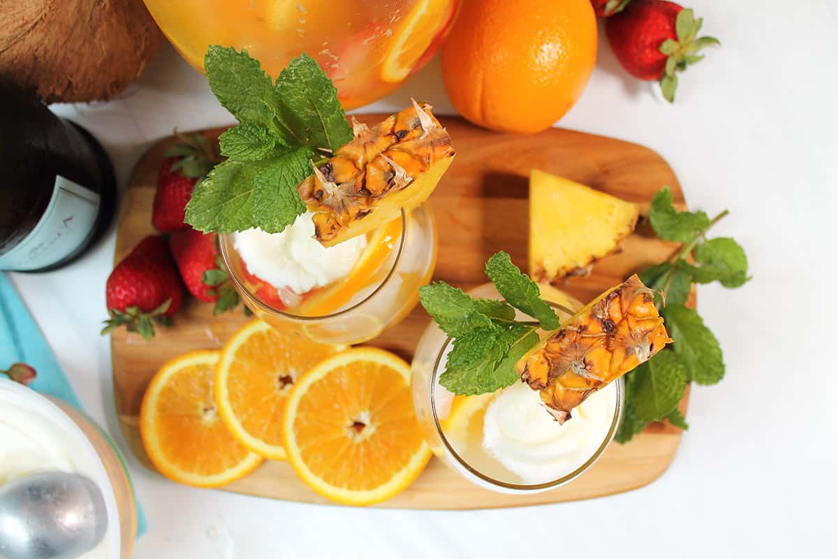 Overhead of two glasses of sangria garnished with pineapple and mint.