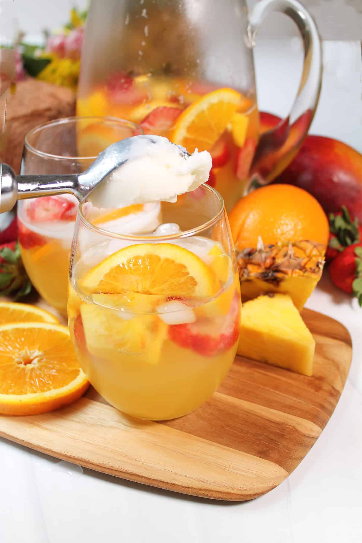 Scooping pineapple sorbet into sangria.