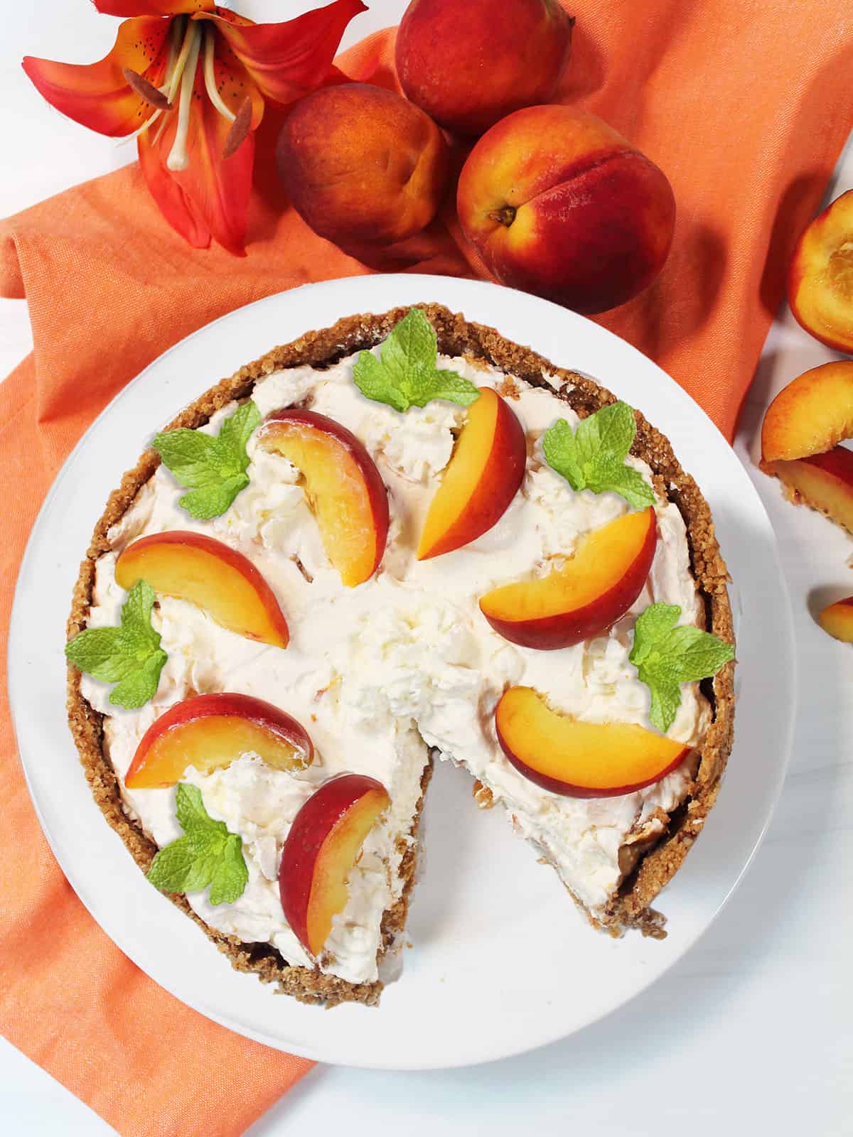 Overhead of no bake peach cheesecake with slice out and mint garnish.