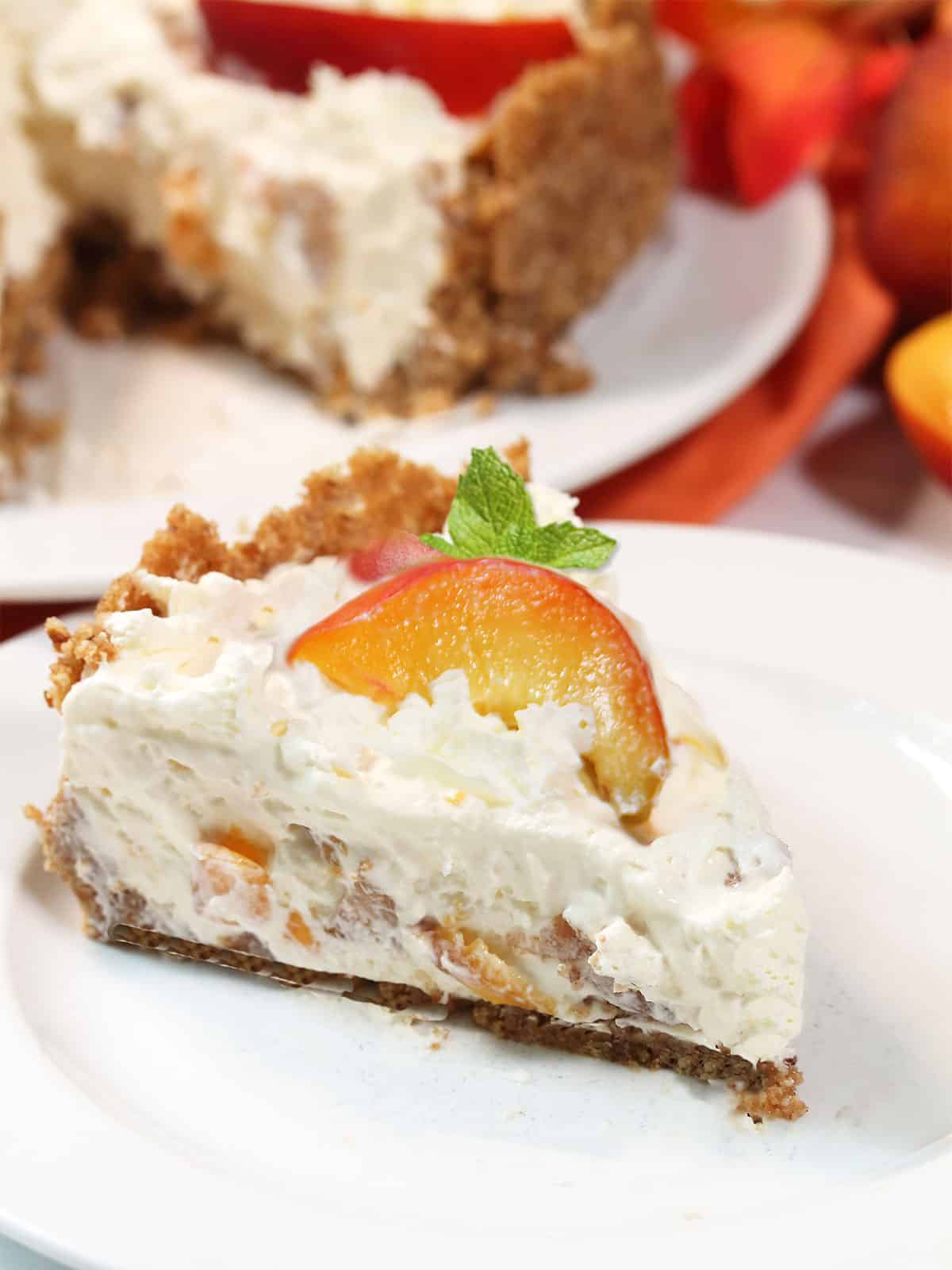 Slice of no bake cheesecake with peach and mint on top.