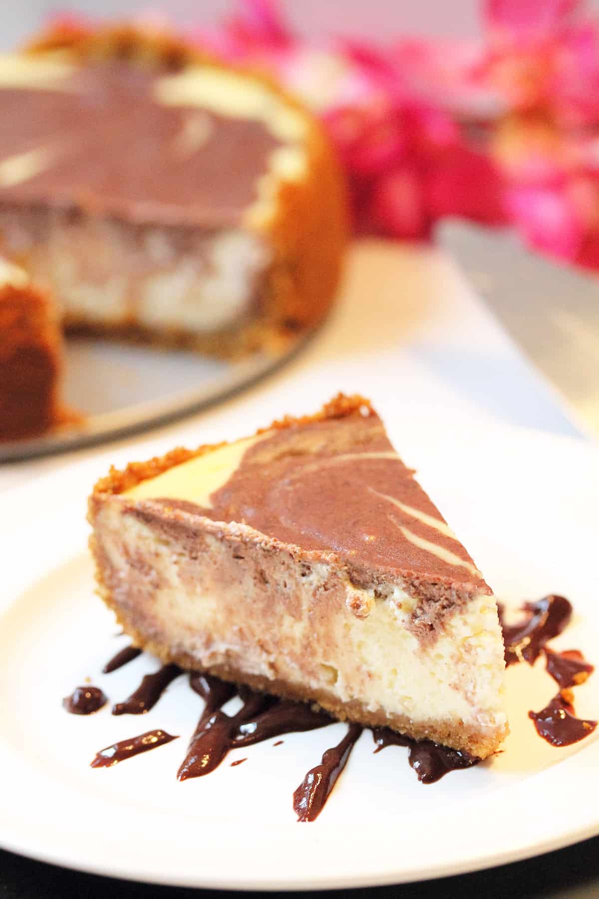 Closeup of slice of chocolate marble cheesecake on top of chocolate drizzle.