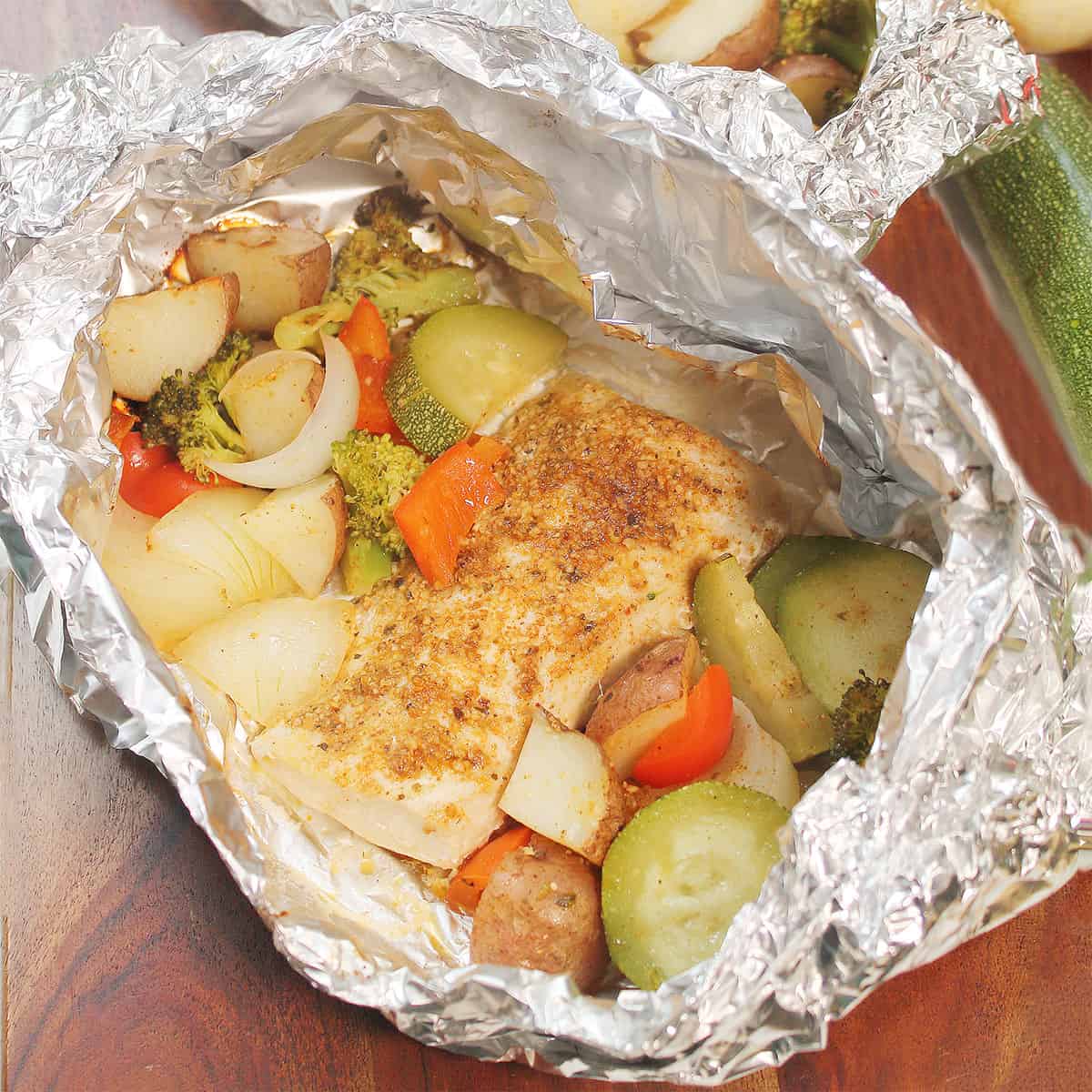 Grilled mahi mahi with vegetables in open packet.