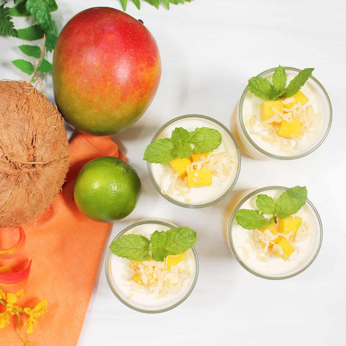 Overhead of four garnished panna cotta with mango.