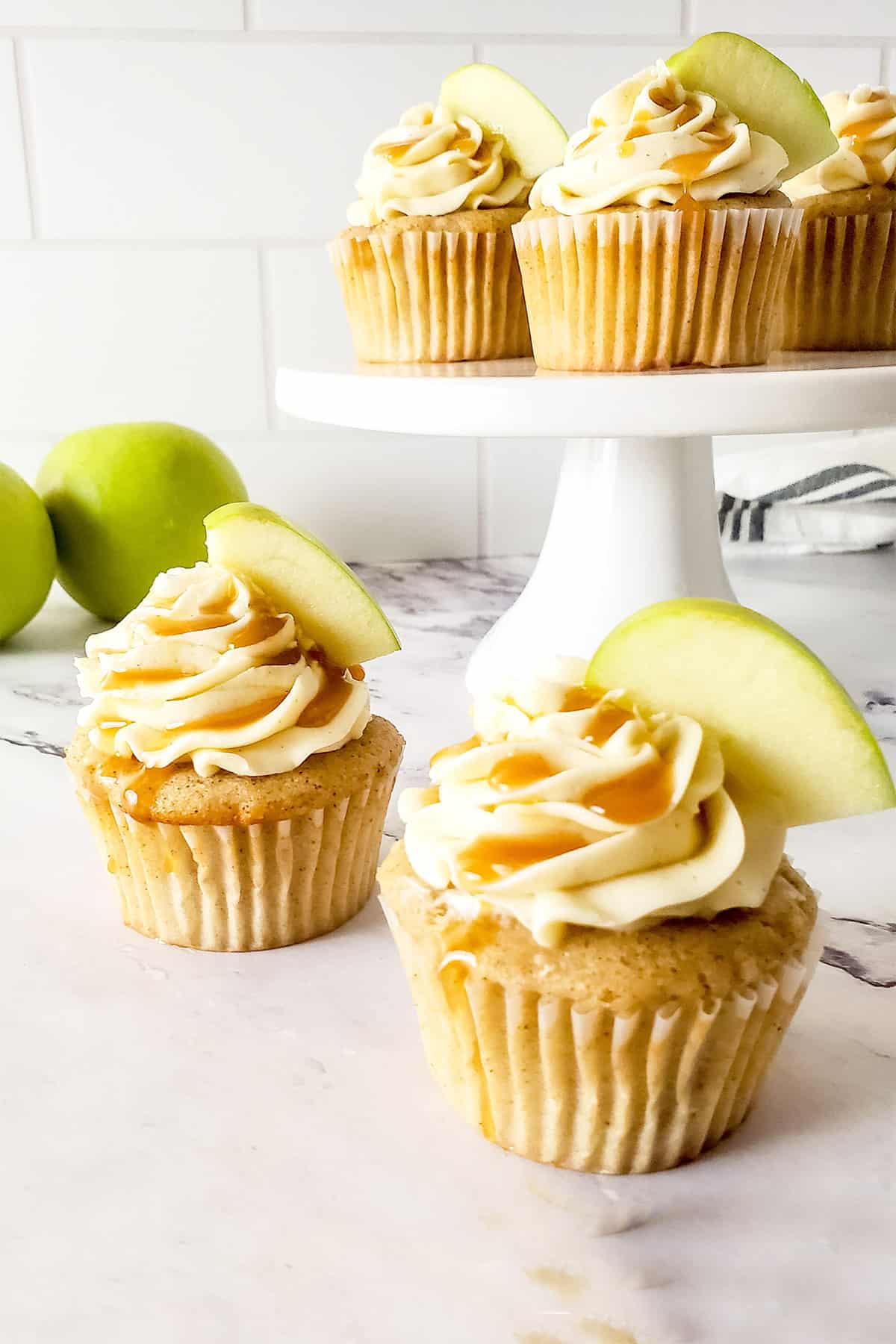 Two Caramel Apple Cupcakes with cake stand of cupcakes.