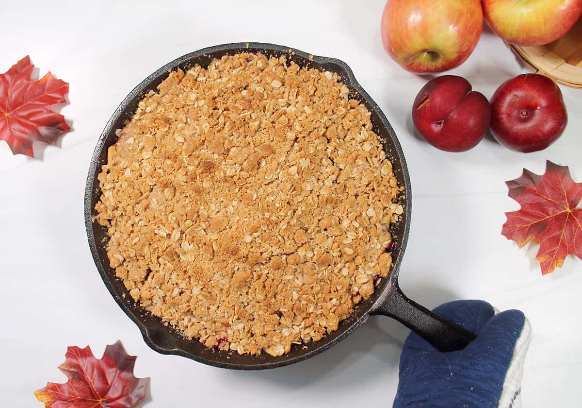 Plum crumble with oats in iron skillet.