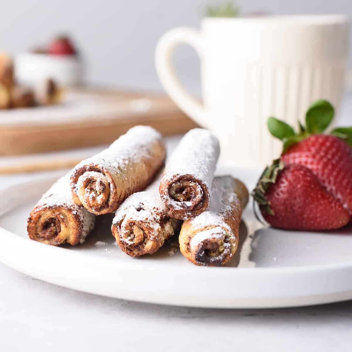 Closeup of rollups on white plate with mug.