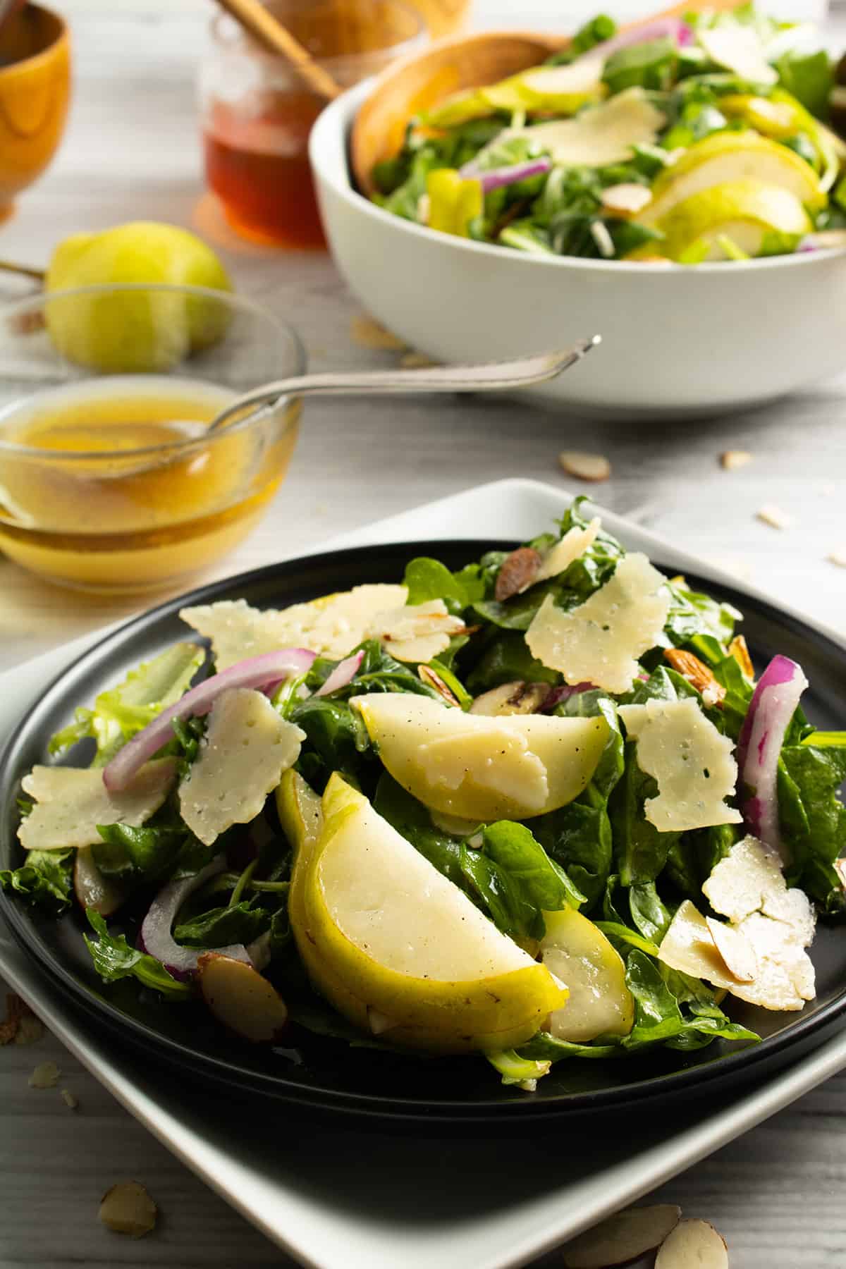 Serving of Rocket Salad with Pear in front of full bowl.