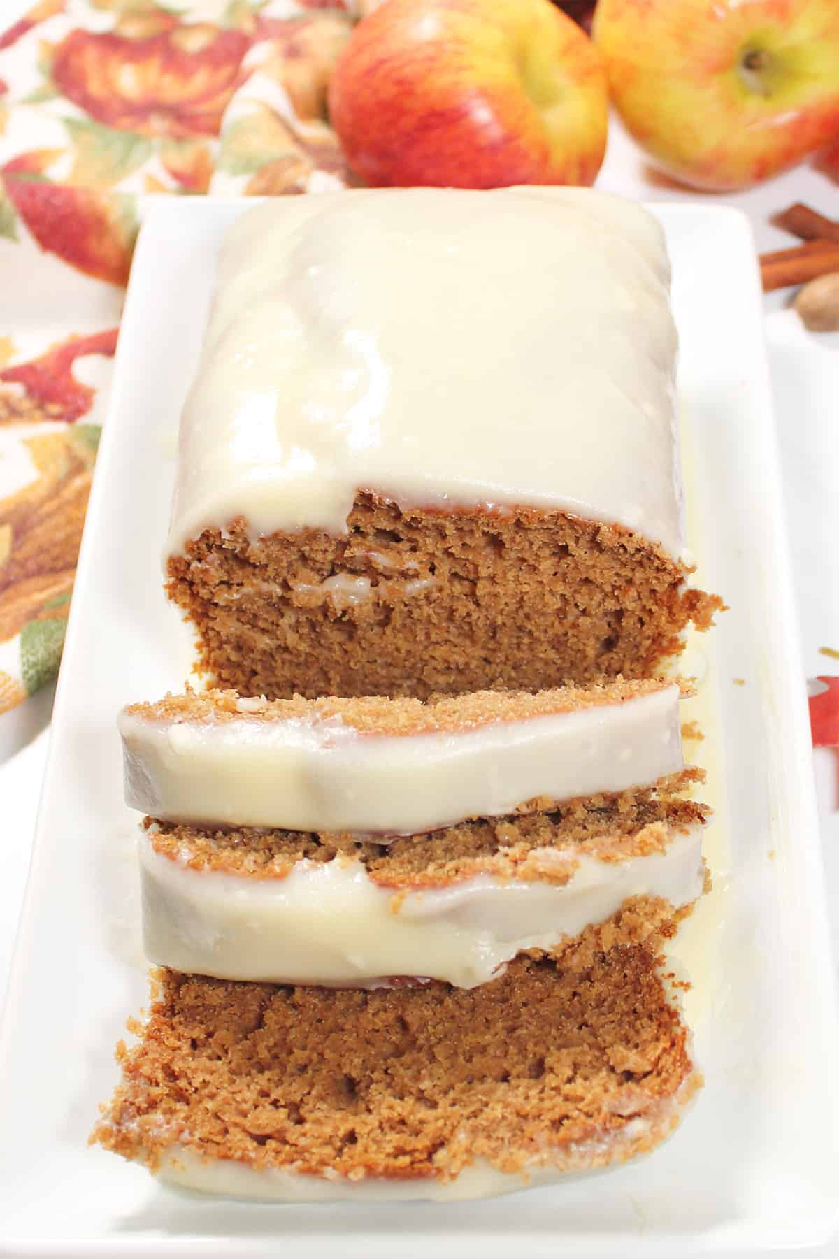Sliced apple butter cake on white platter with apples.