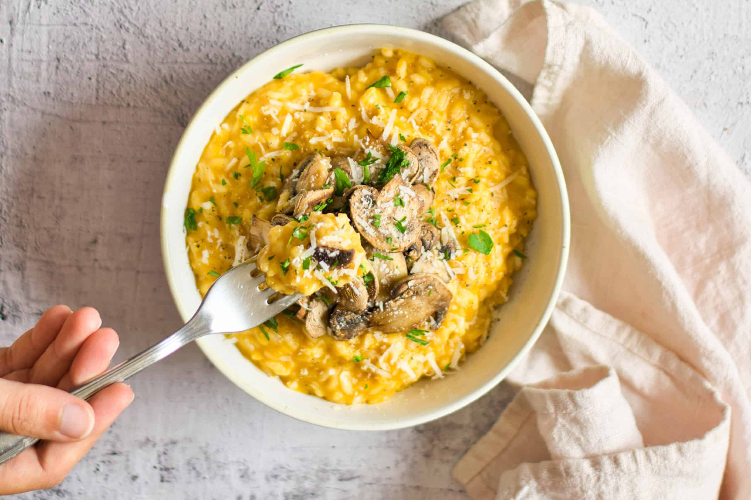 Single bowl of risotto with bite on fork.