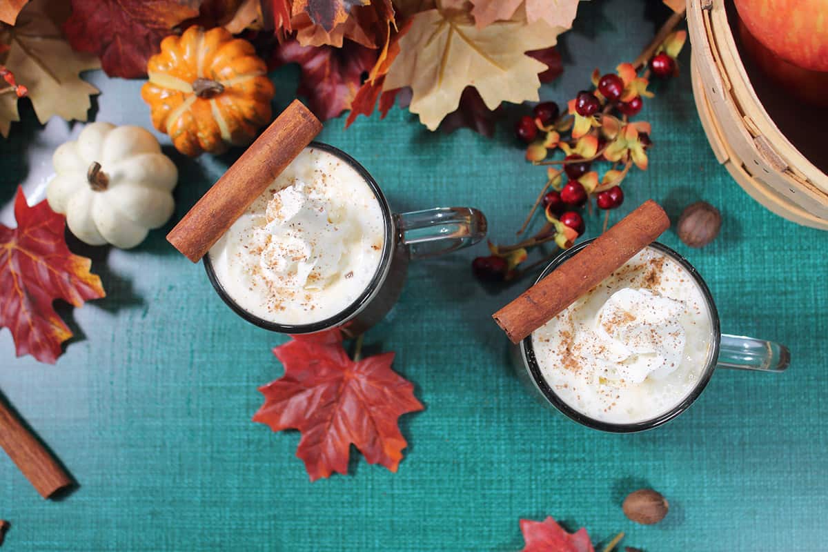Overhead of two apple cider cocktails with fall leaves.