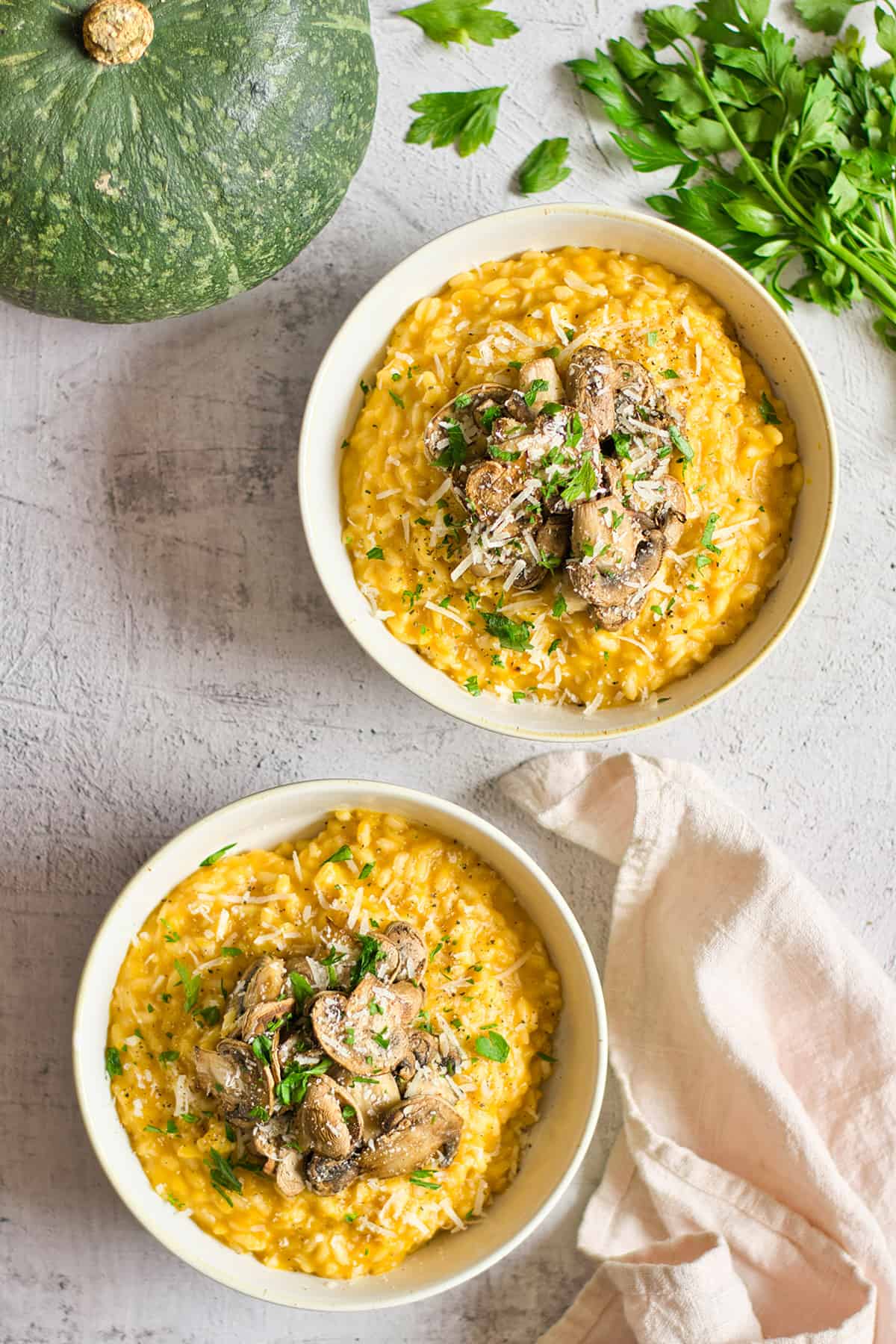 Two bowls of garnished pumpkin risotto.