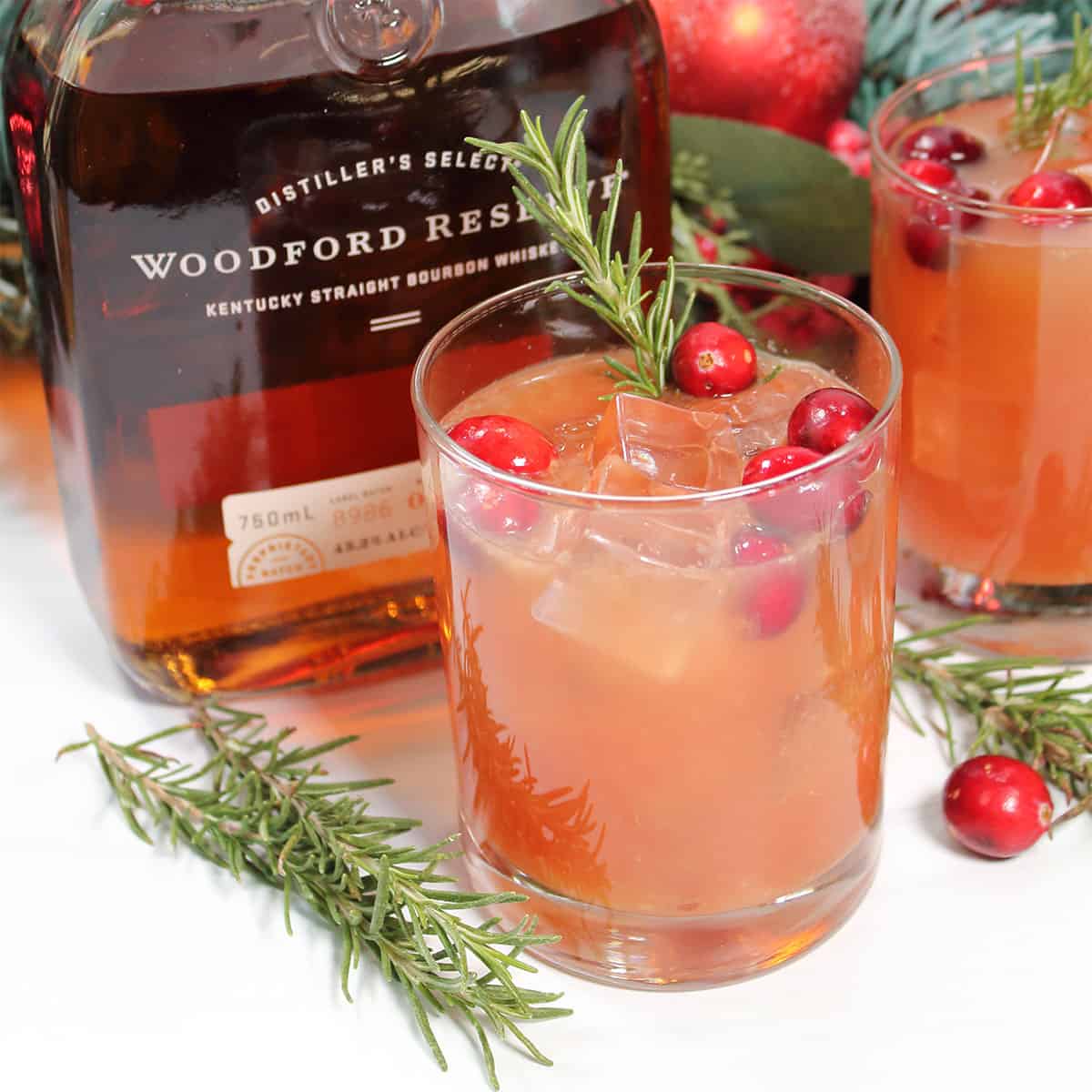 Cranberry bourbon cocktail in front of bourbon bottle.