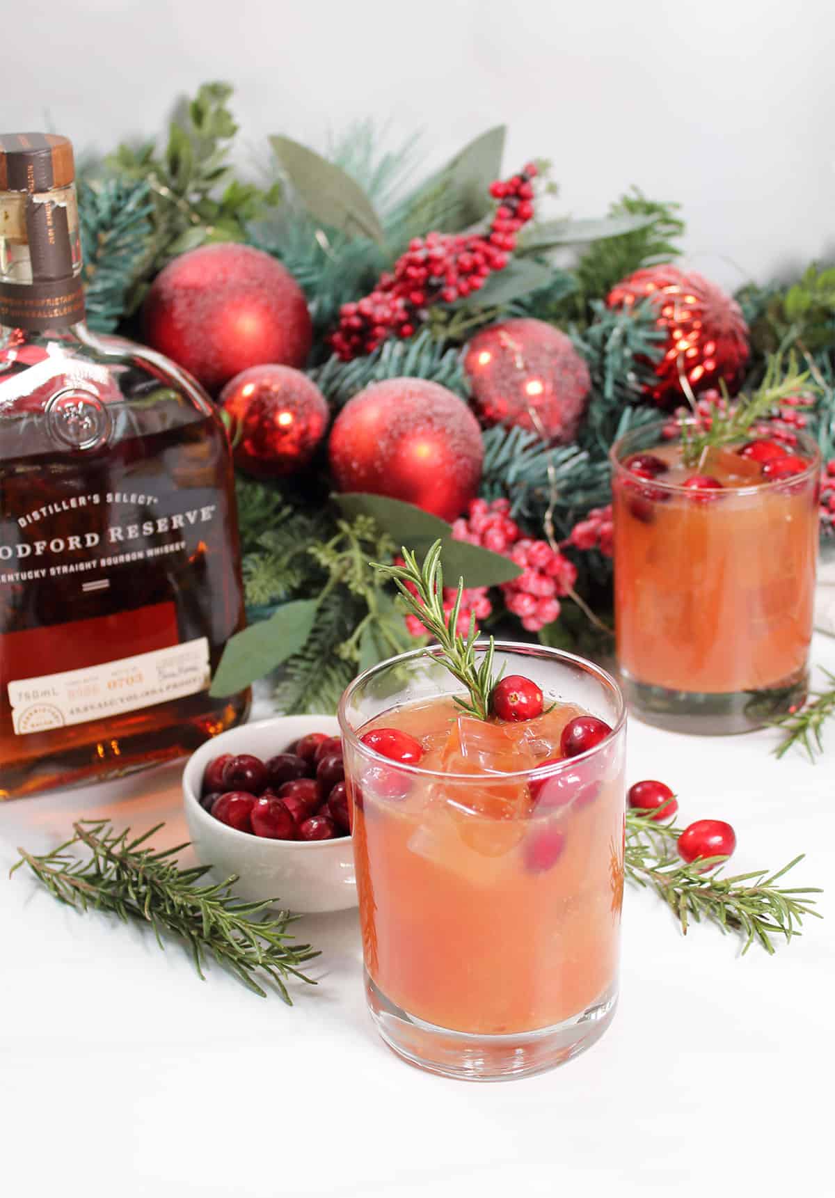 Two Cranberry Bourbon cocktails in front of garland.