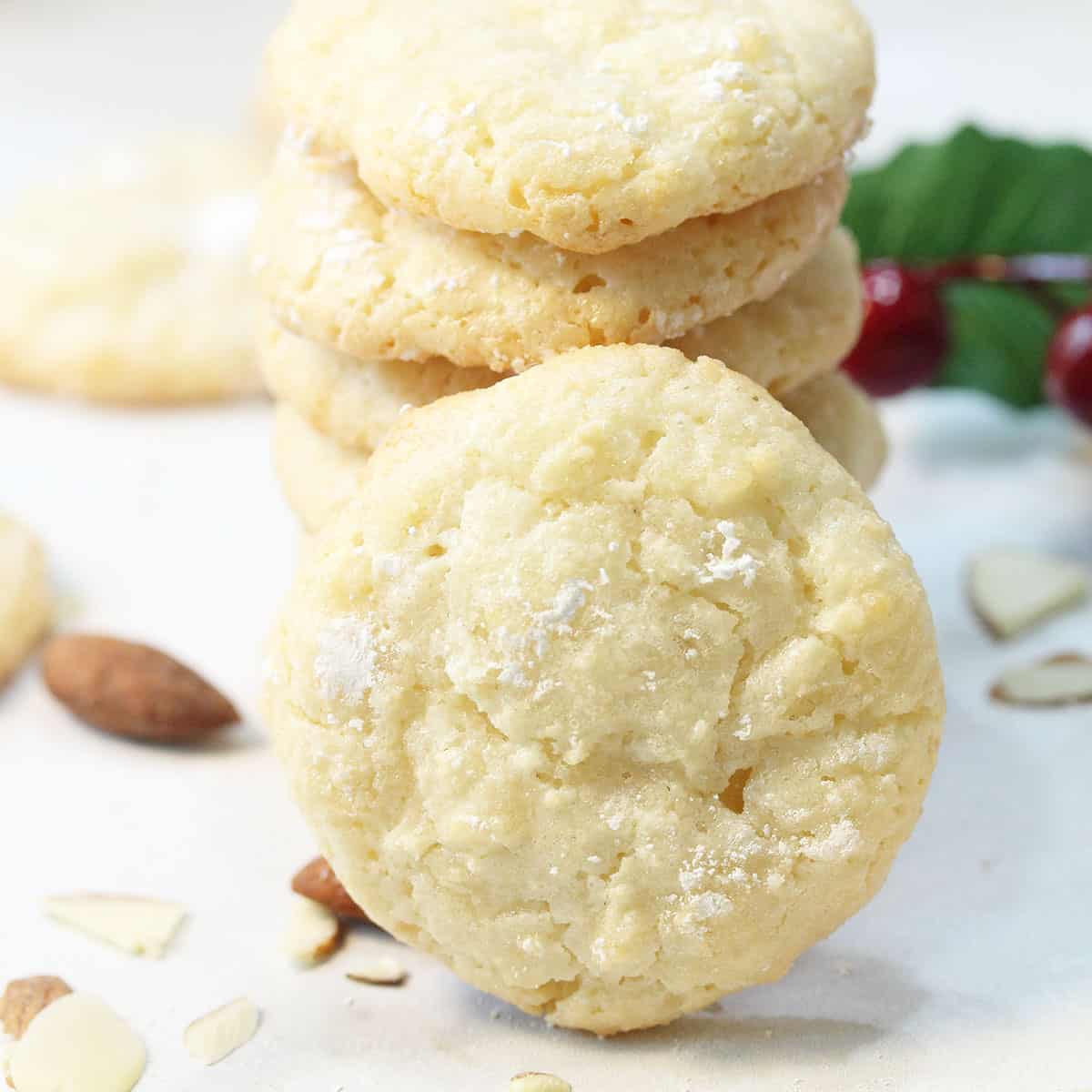 Closeup of stacked Almond Cloud Cookies with scattered almonds.