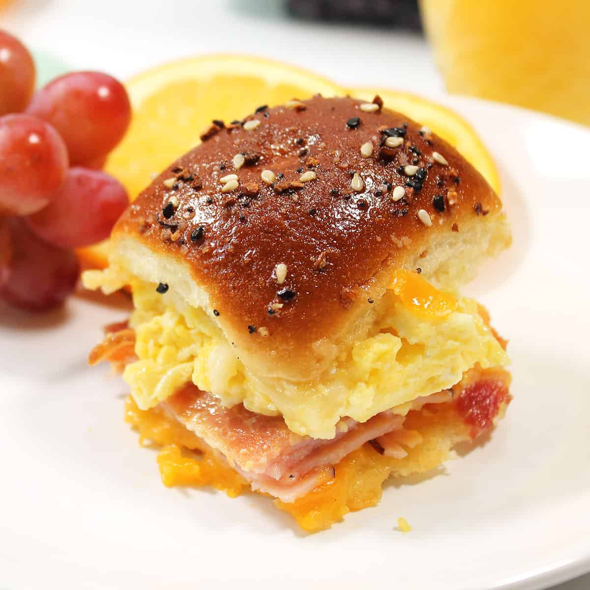Hawaiian roll slider on plate with fruit.