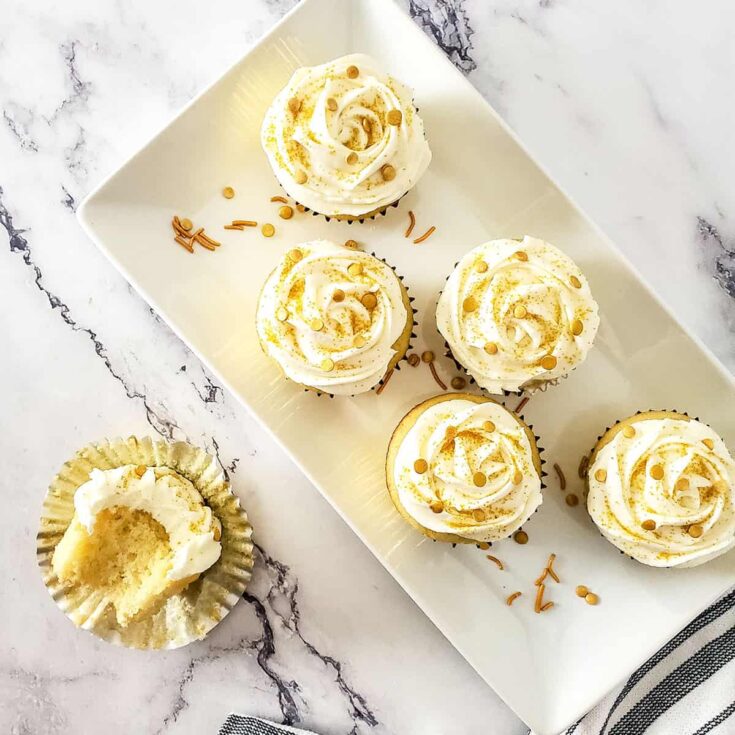 Overhead of cupcakes on platter with halved one in front.