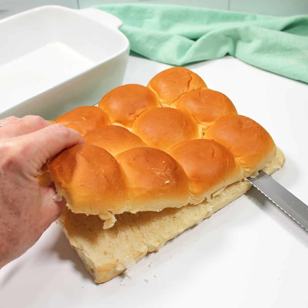 Slicing Hawaiian rolls in half